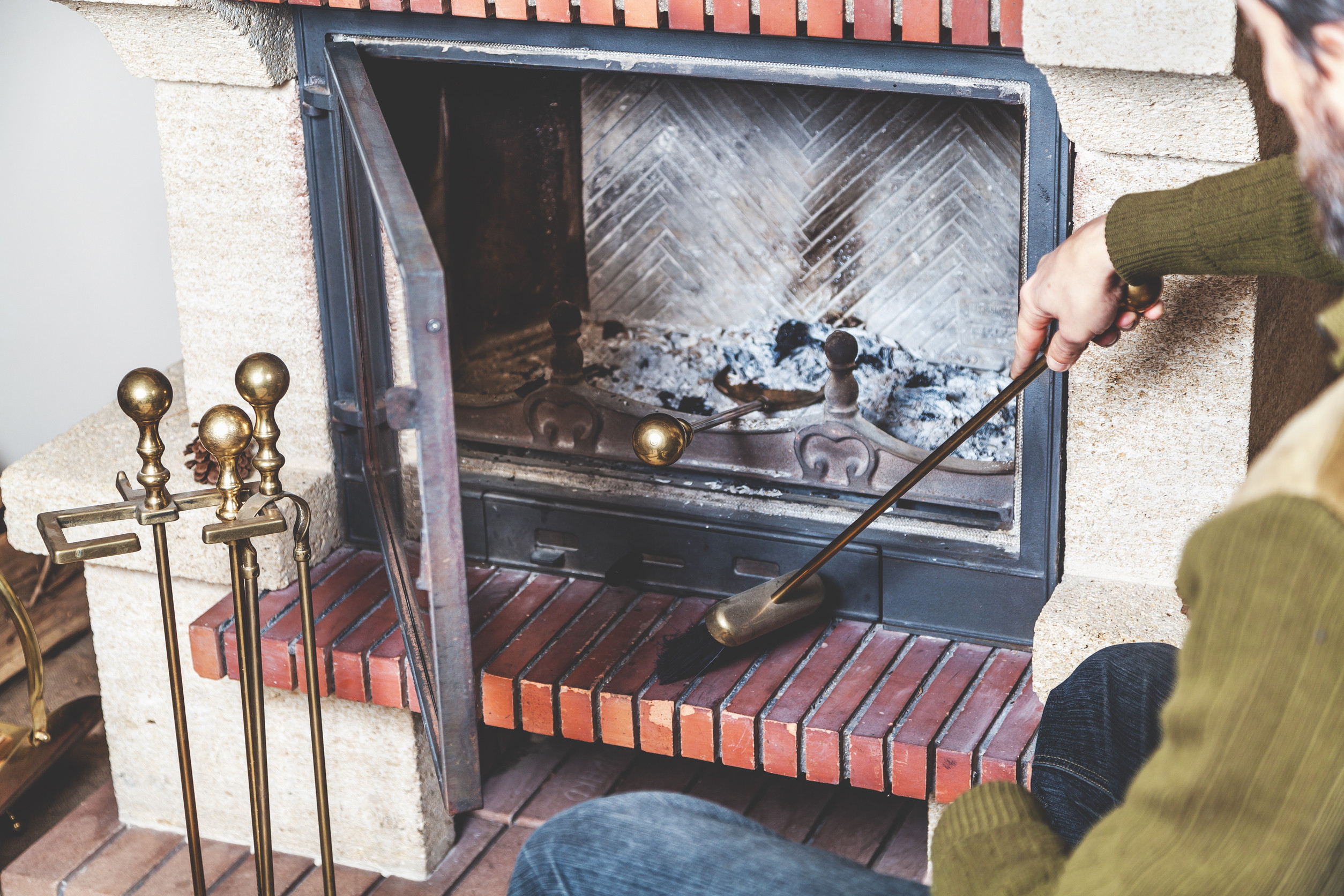 man cleans the furnace of fire with a spatula and brush on a long handle man cleans the furnace of fire with a spatula and brush on a long handle