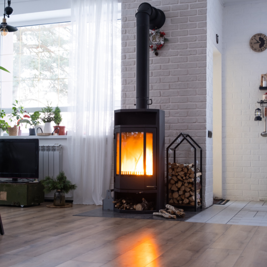 Black stove, fireplace in interior of house in loft style. Alternative eco-friendly heating, warm cozy room at home, burning wood<br />
